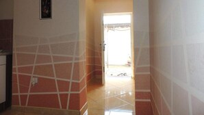 Um corredor com piso ladrilhado e uma porta que dá para uma área externa iluminada.