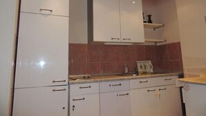 Cozinha com armários brancos, painel de azulejos e bancada.