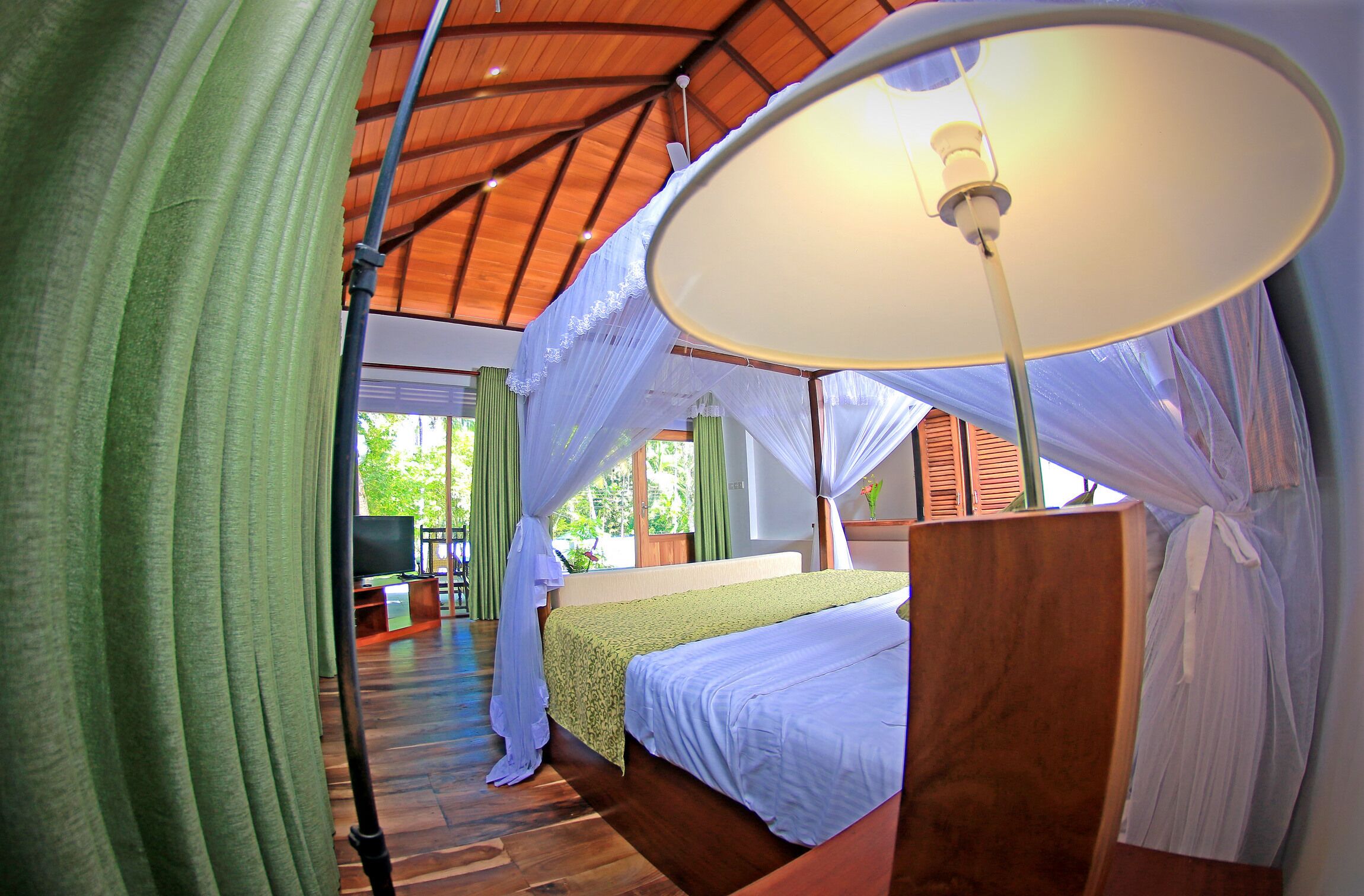 A room with a bed, a television, and a large window.