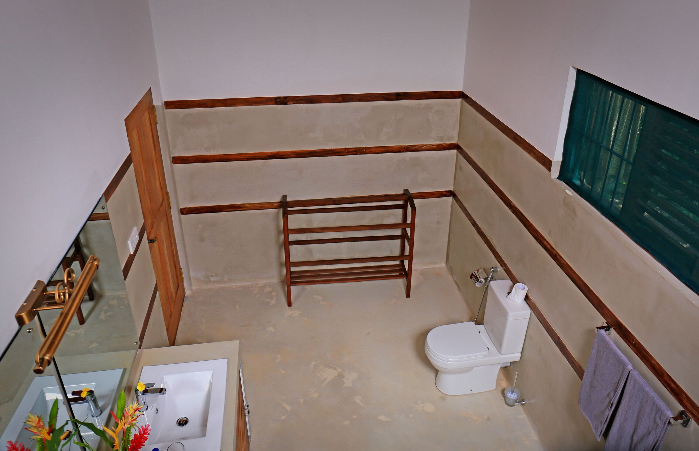 A bathroom with a wooden-framed shower, a toilet, a sink, and a mirror.