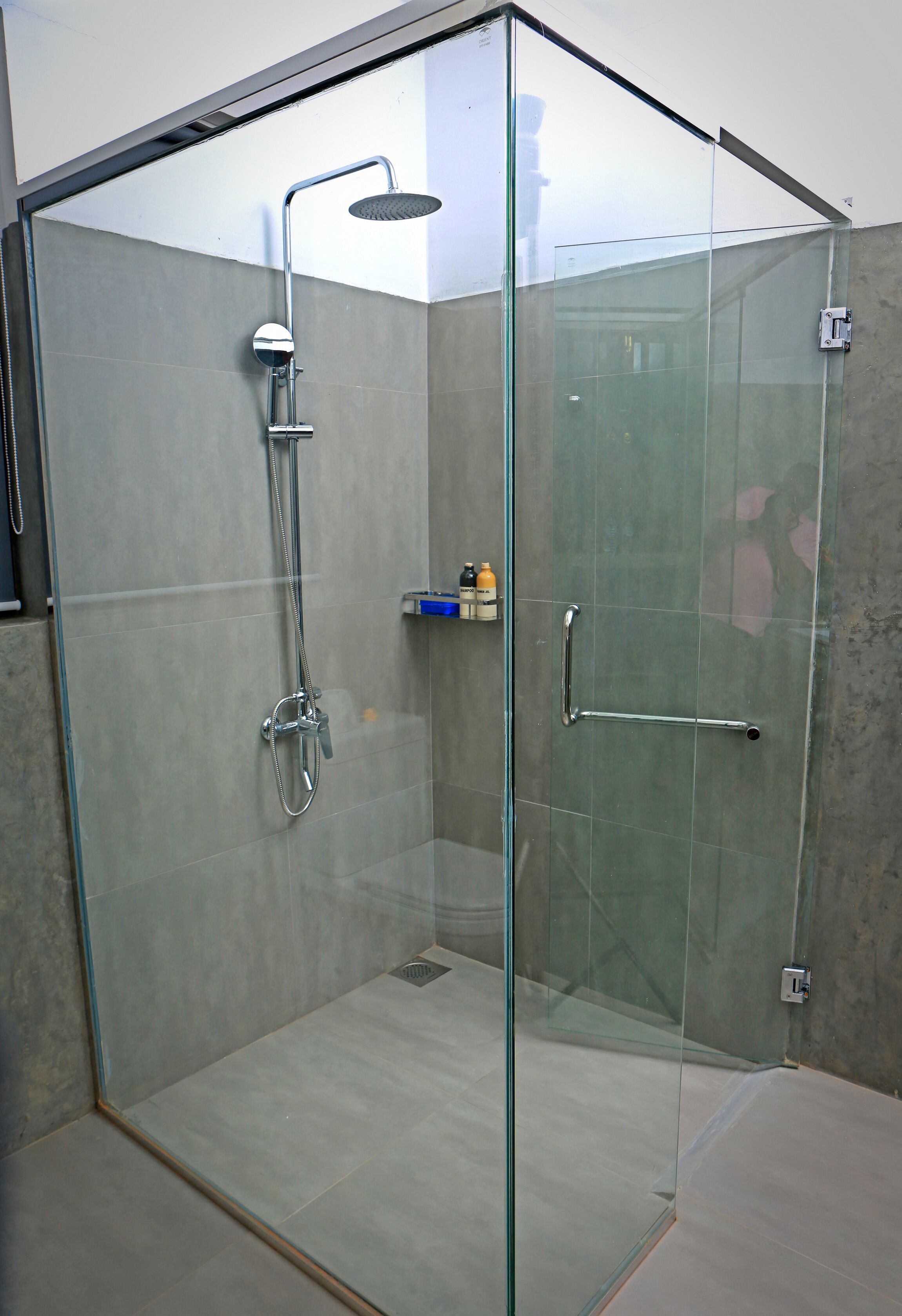 A glass-enclosed shower area with a handheld showerhead and a wall-mounted faucet.