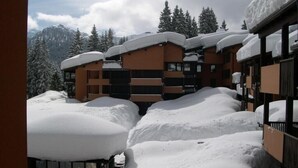 Ein schneebedecktes Gebäude mit mehreren Balkonen und einer Bergkulisse.