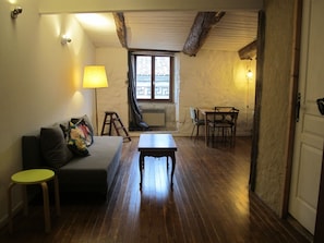 Una habitación acogedora con suelo de madera, un sofá, una mesita y una ventana con vistas.