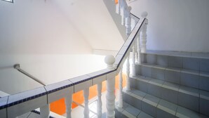 A staircase with white balusters and blue-tiled handrails, leading to an upper floor.