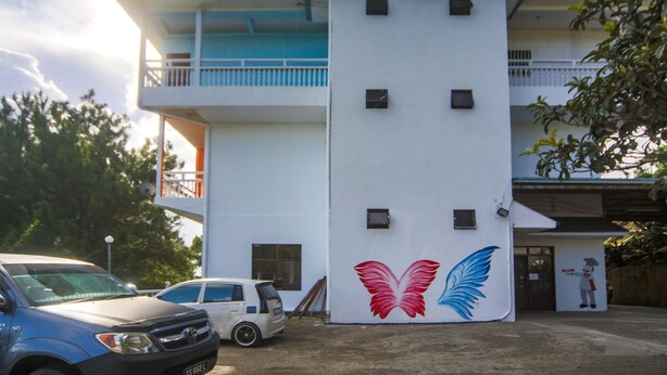 A building with a white exterior, a balcony, and a mural of wings. - OYO 89537 Fairy Garden Resort (Ranau)