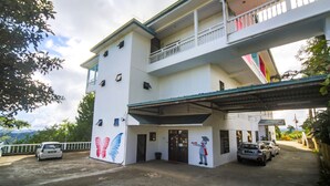 A two-story building with a balcony on the upper floor, a covered entrance, and a mural on the side.