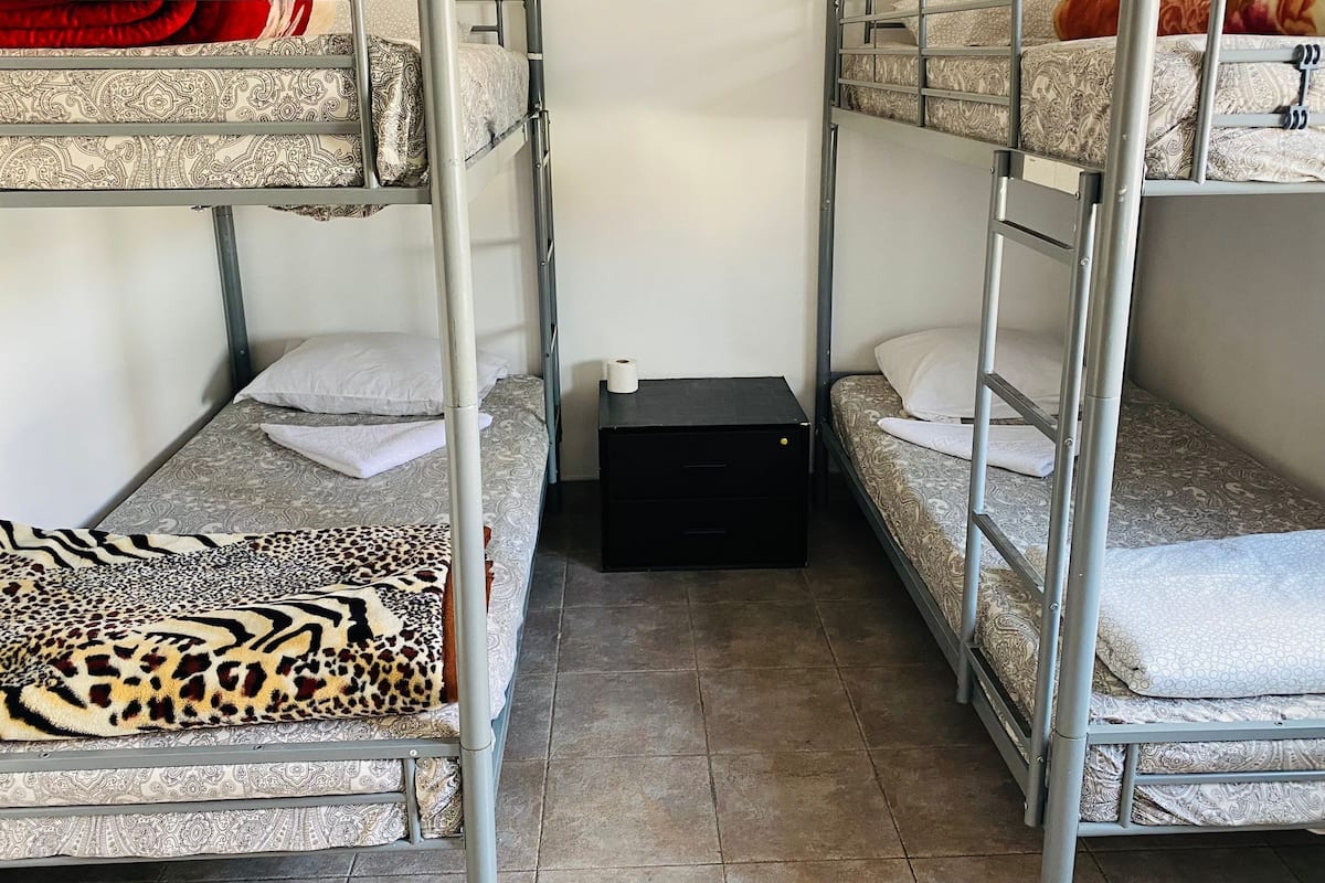 Une chambre avec un lit superposé, une couvre-lit à motifs, une couverture à imprimé léopard et une petite table de chevet noire.