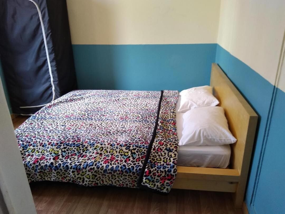 A small, single-bed room with a blue and white color scheme, a leopard print bedspread, and a wooden headboard.