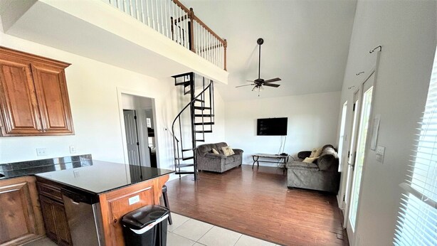 A spacious kitchen with a central island, a dining area with a sofa, and a staircase leading to an upper level.