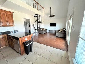 A spacious kitchen with a central island, a dining area with a sofa, and a staircase leading to an upper level.