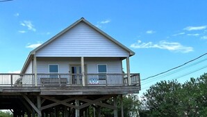 A two-story house with a balcony on the ground floor and a 'For Sale' sign.