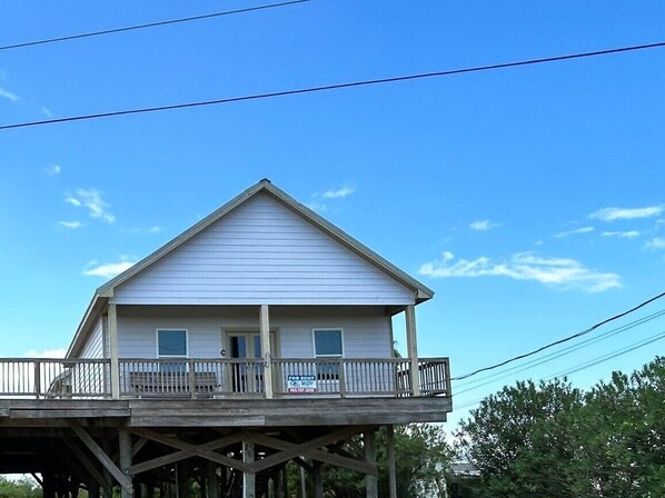 A two-story house with a balcony on the ground floor and a 'For Sale' sign.