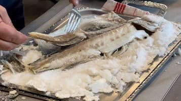 A person using tongs to handle fish on a tray.