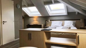 Un dormitorio con tragaluces, una cama, un escritorio y un armario.