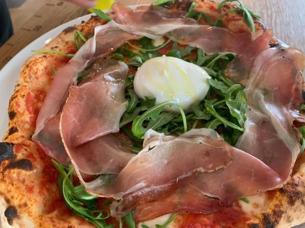 A pizza with prosciutto and arugula.