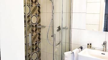 A modern bathroom with a glass-enclosed shower, a white sink, and a mirror above it.