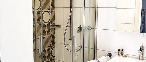 A modern bathroom with a glass-enclosed shower, a white sink, and a mirror above it.