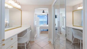 A modern bedroom with a large bed, a desk with a chair, a large mirror, and a balcony with a view. - Majestic T2-1606 - Fabulous Three Bedrooms Condo! (Panama City Beach)