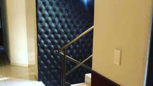 A staircase with a black tufted wall and a metal handrail. - Naldorado Executive Villa (Mbombela)