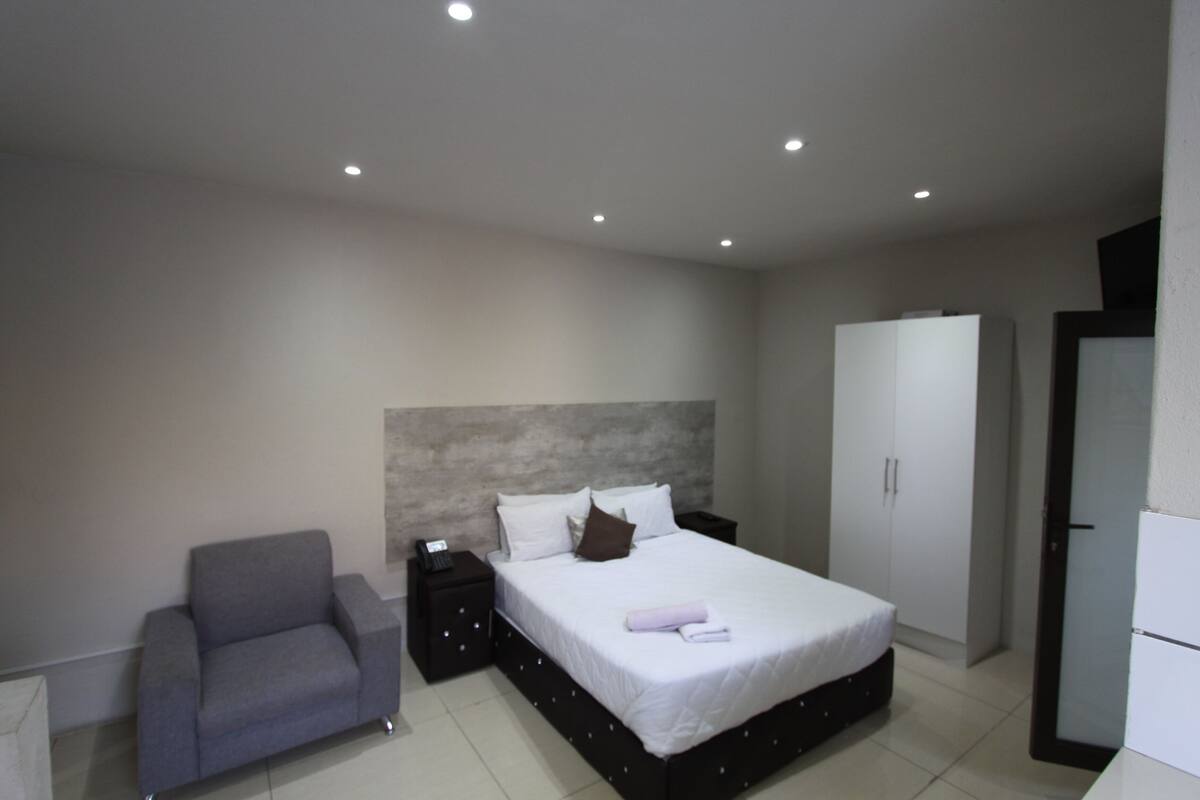 A modern bedroom with a bed, a nightstand, a sofa, and a wardrobe.