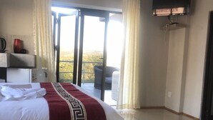 A hotel bedroom with a large bed, a TV mounted on the wall, and a balcony with curtains. - Naldorado Executive Villa (Mbombela)