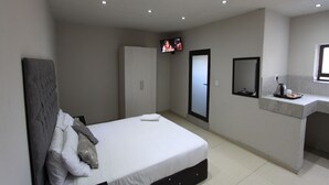 A bedroom with a bed, a television, a wardrobe, and a bathroom counter. - Naldorado Executive Villa (Mbombela)