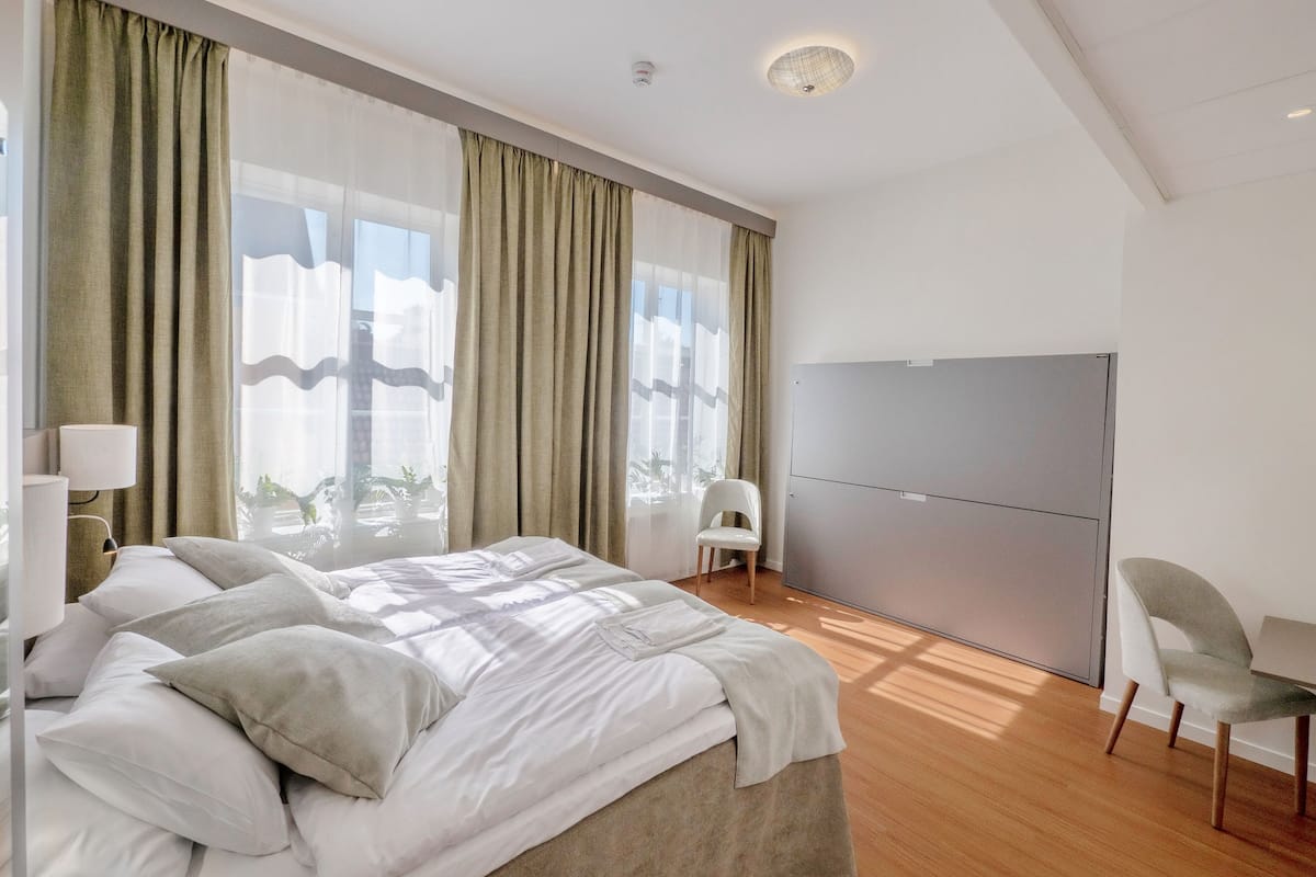 A modern hotel room with a large bed, a desk, and a chair.