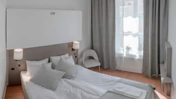 A hotel room with a bed, a chair, a TV, and a window with curtains.