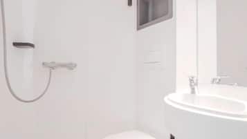 A modern bathroom with a white toilet, a shower, and a sink.