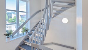 A modern interior with a spiral staircase, a large window with a view of buildings, and a small balcony with plants. - Hamnhotellet (Vastervik)