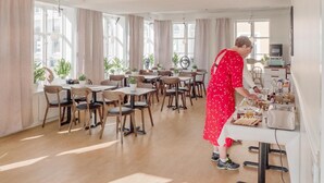 A spacious dining area with multiple tables and chairs, large windows, and potted plants. - Hamnhotellet (Vastervik)
