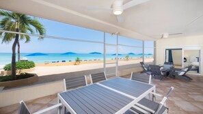 Un balcón con vistas a la playa y al océano, con una mesa y sillas.
