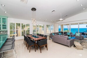 Un amplio salón con mesa de comedor, sofás y vistas al mar.