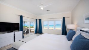 A hotel room with a bed, a TV, a desk, and a view of the beach. - Laguna Del Mar (Seven Mile Beach)