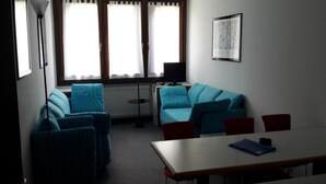 A room with a blue sofa, a table, and a radiator. - Residence Rio Falzè ~ TWO-ROOM APARTMENT TYPE A1 # 28 (Campo Carlo Magno)