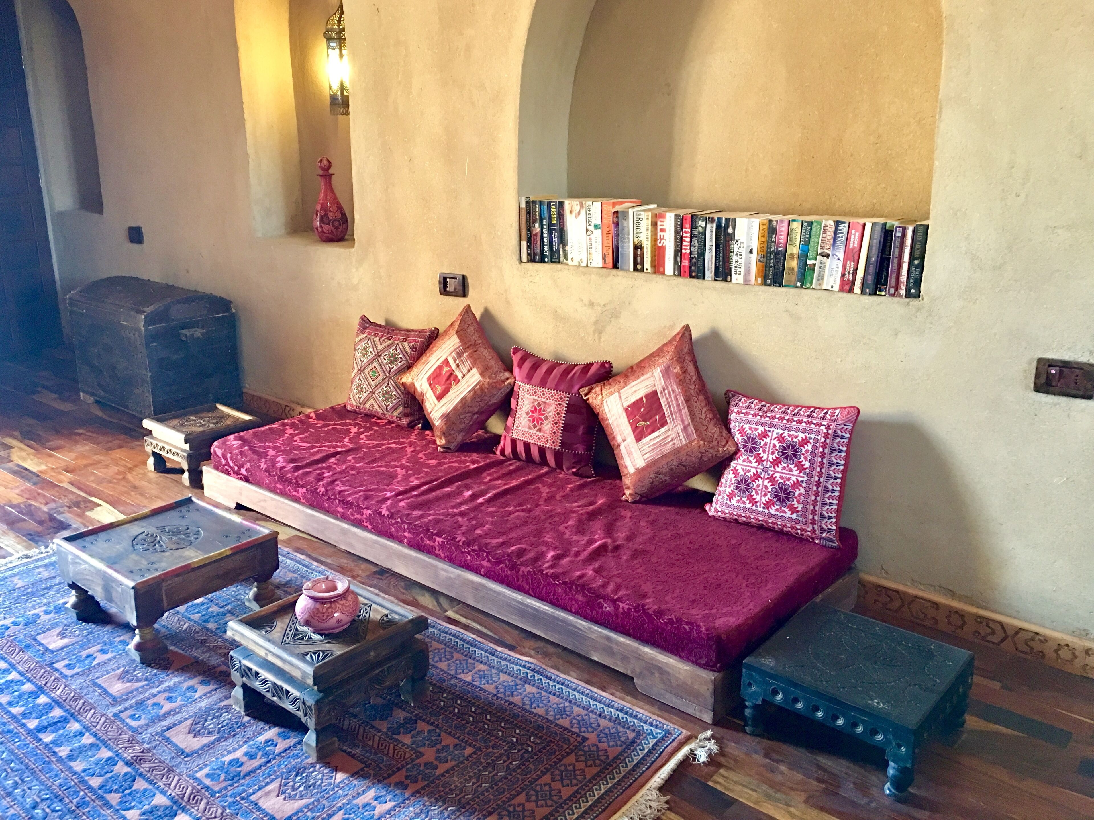 A cozy living room with a sofa, patterned cushions, a bookshelf, and traditional decor.