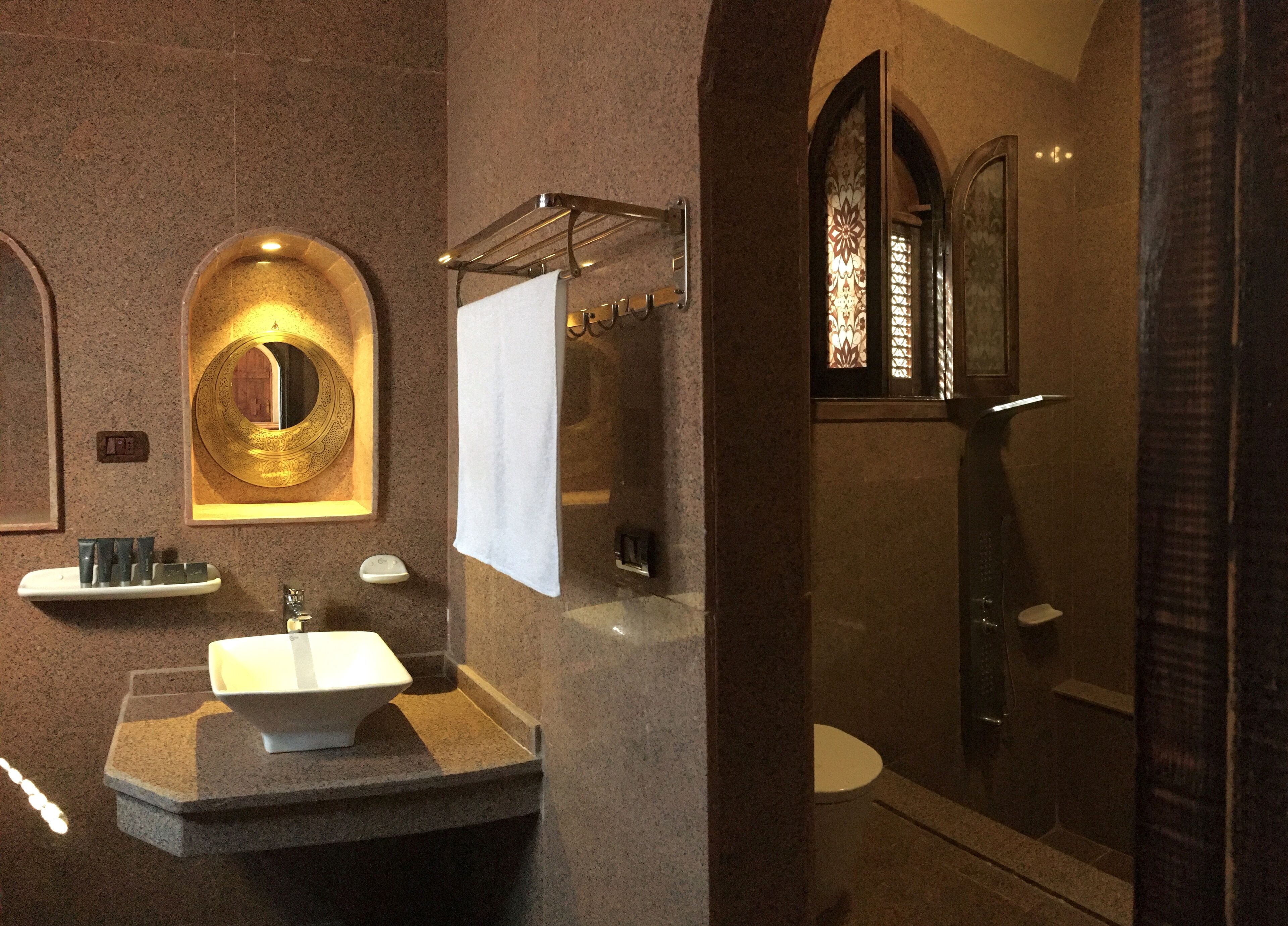 A modern bathroom with a freestanding sink, a large mirror, a towel rack, and a shower area.
