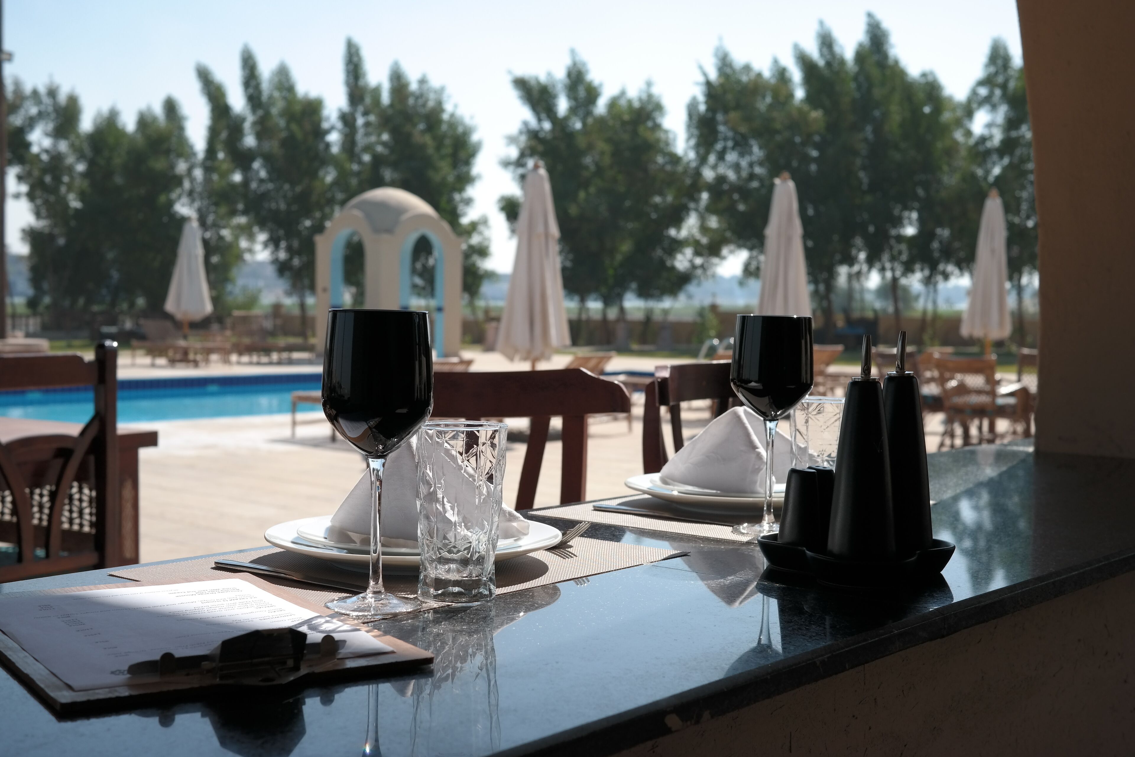 Une table à manger avec un menu, deux verres à vin et un présentoir à menus.