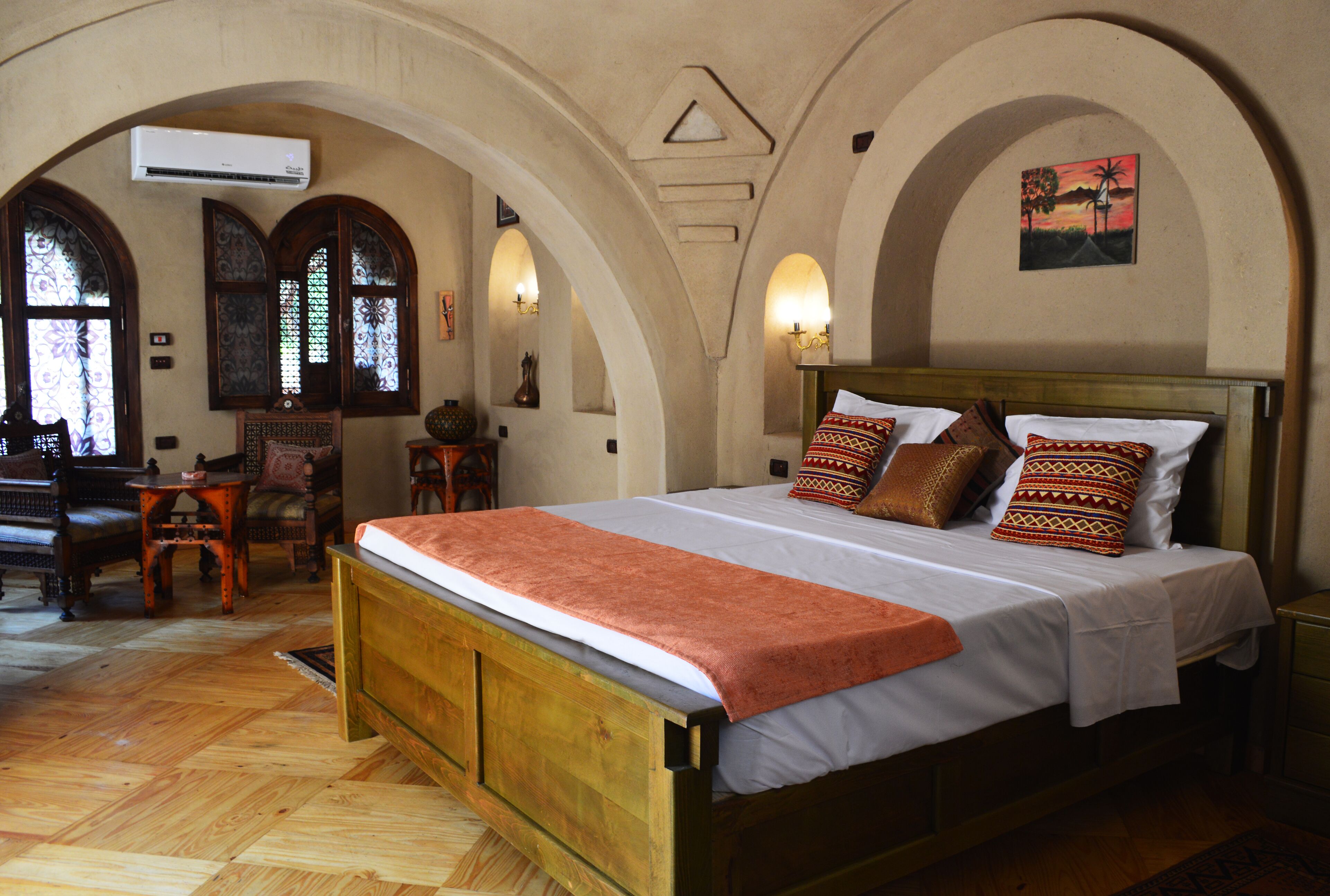 A bedroom with a wooden bed, arched ceiling, and a view of the outside through a window.