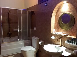Un baño con ducha, inodoro, lavamanos y un espejo decorativo.