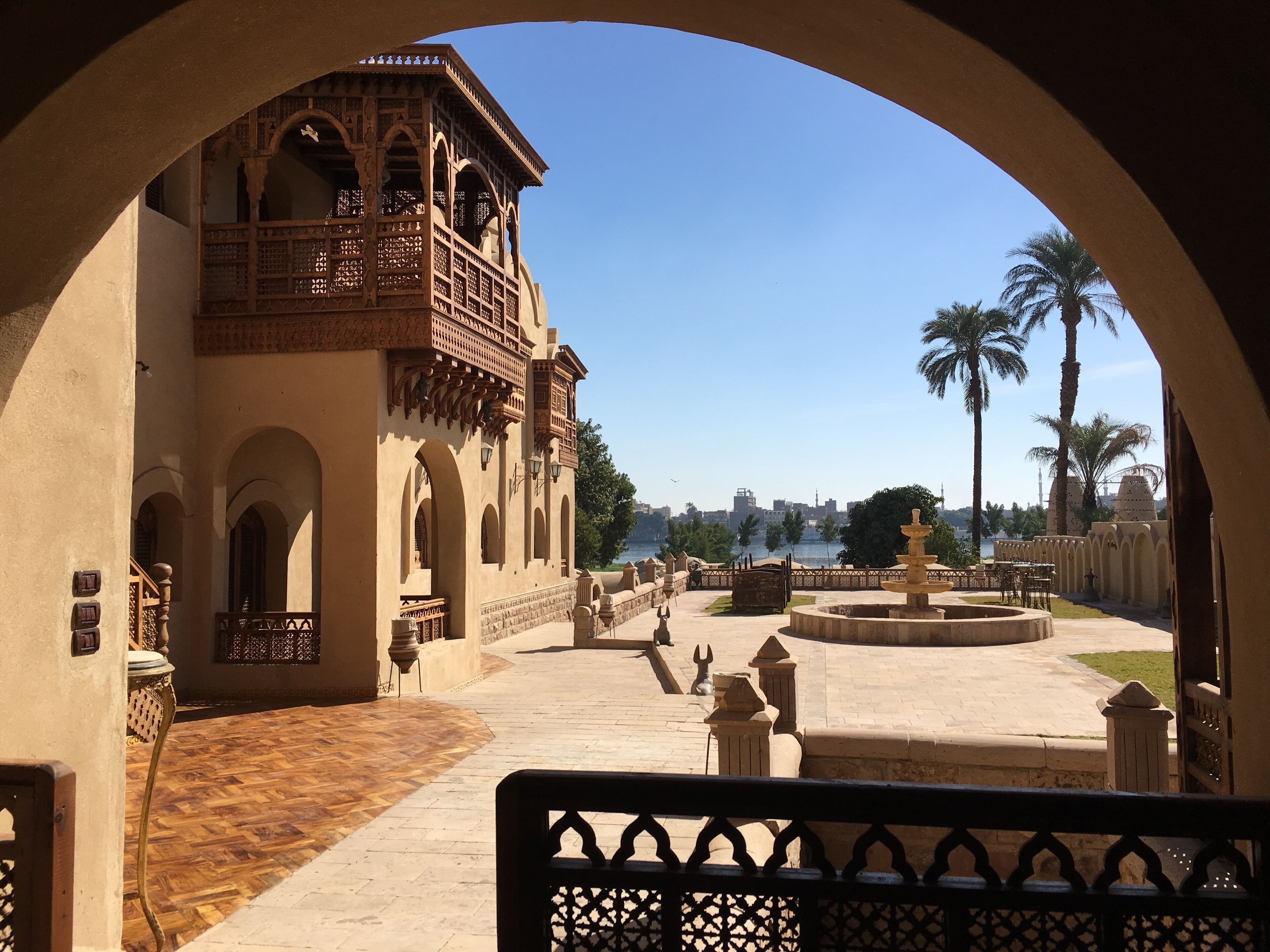 Un patio con una fuente, palmeras y vistas al horizonte de una ciudad.