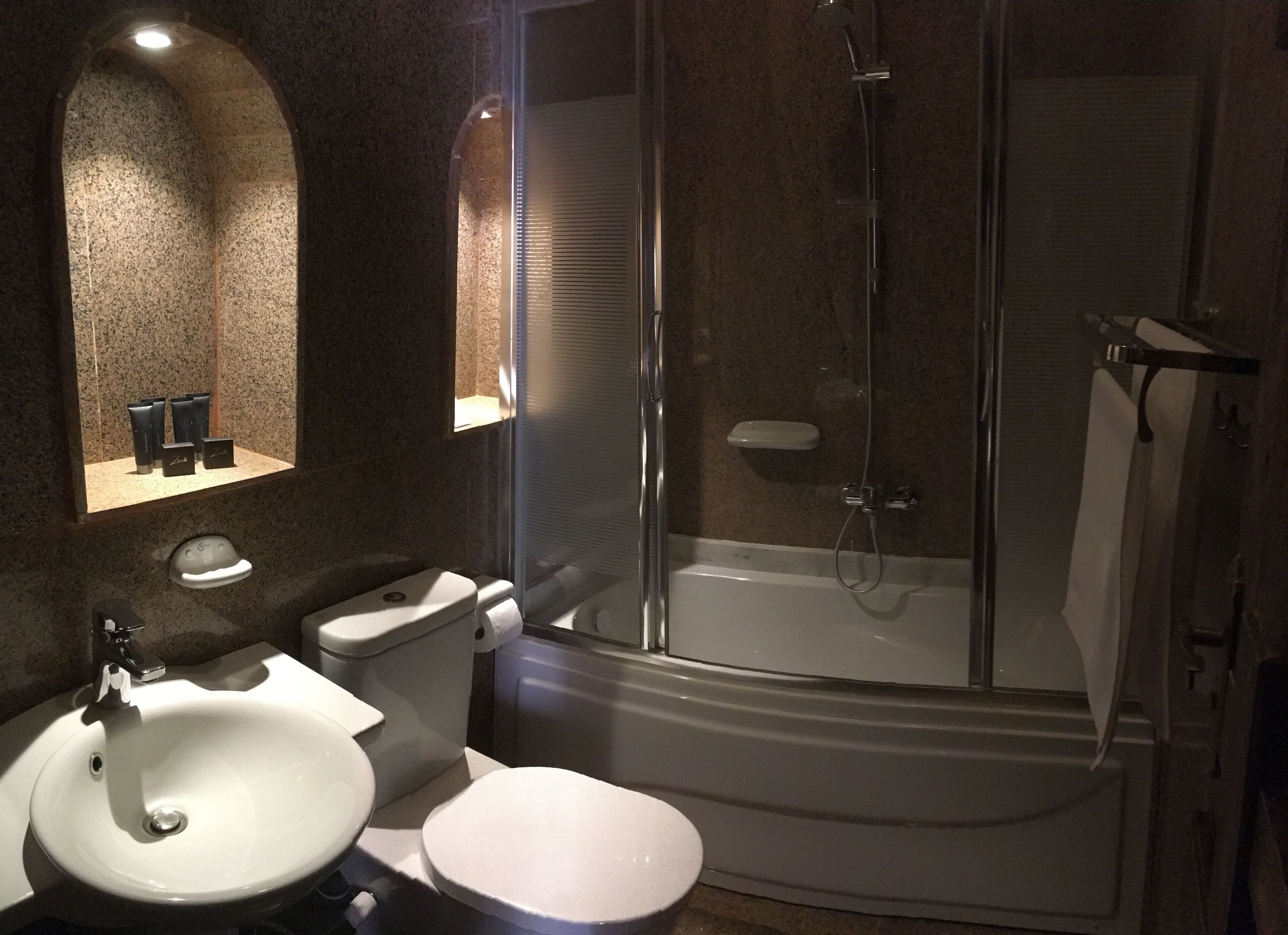 A modern bathroom with a glass-enclosed shower, a white toilet, and a sink.
