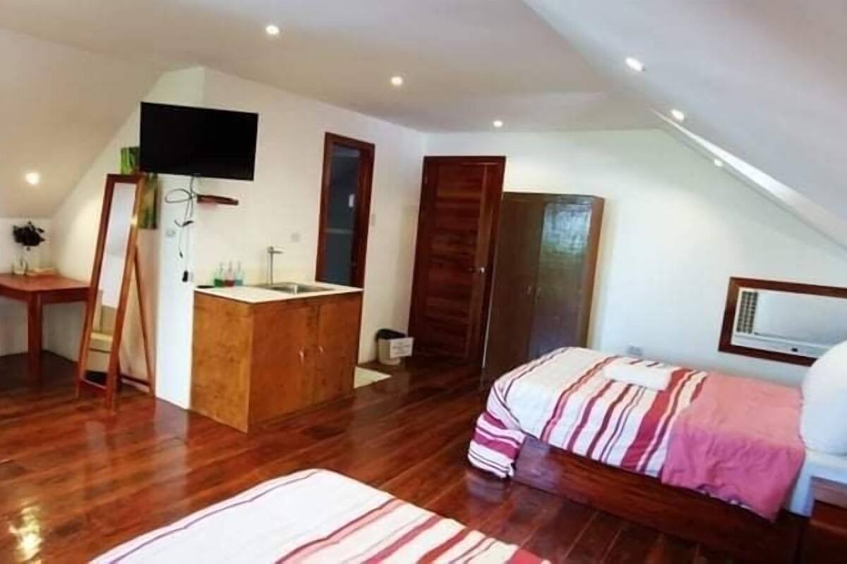 A bedroom with a bed, a sofa, a desk, and a TV.