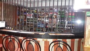Een bar met een toonbank, krukken en flessenkasten.