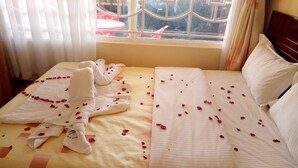 Een hotelkamer met een bed versierd met rozenblaadjes en een handdoek.