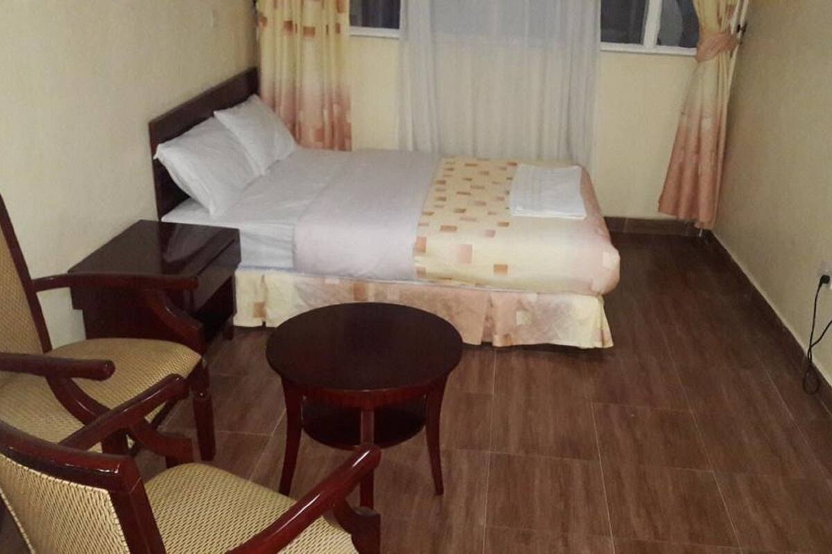 Une petite chambre à coucher, bien rangée, avec un lit, une chaise, une petite table et une table de chevet.