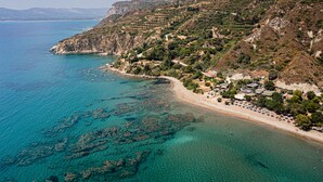 An aerial view of a coastal area with a beach, rocky terrain, and buildings. - Beach front "Andriana Villa" with mini pool and spa (Zakynthos)