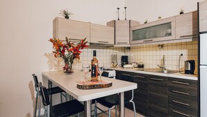 A modern kitchen with a dining area, featuring a white table, black chairs, a vase with flowers, and a coffee machine. - Beach front "Andriana Villa" with mini pool and spa (Zakynthos)
