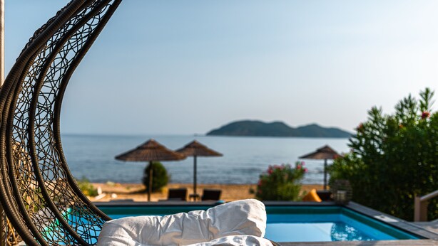 A wicker chair with a white cushion by a pool, with umbrellas and a view of the sea and islands. - Beach front "Andriana Villa" with mini pool and spa (Zakynthos)