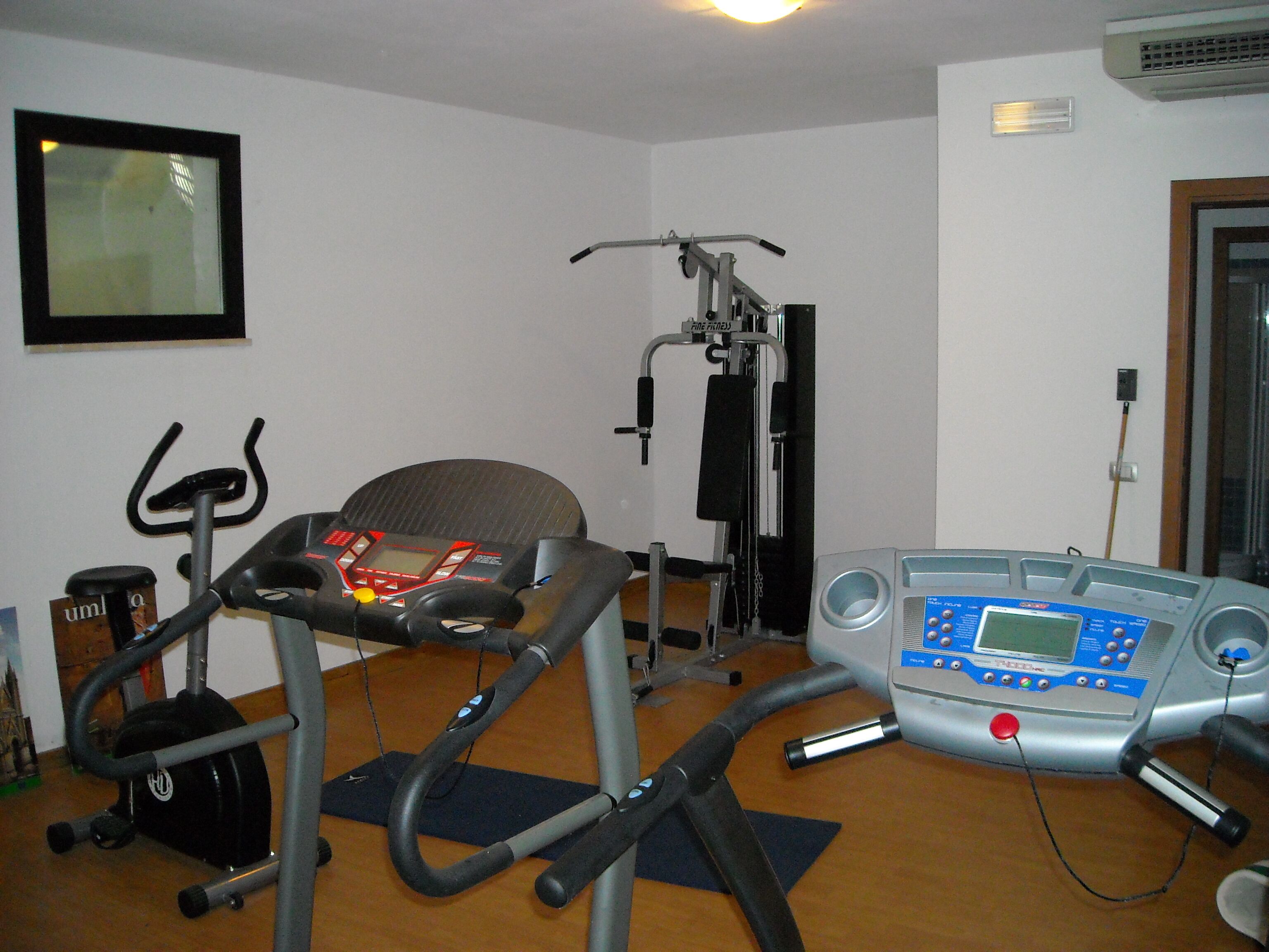 A home gym with an elliptical, a stationary bike, and a treadmill.